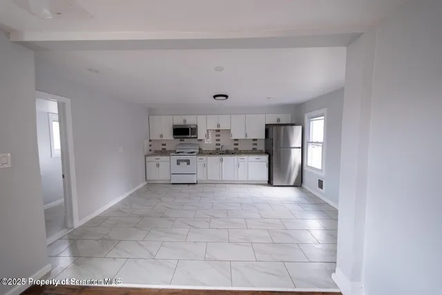 a large white kitchen with a stove a refrigerator and a sink