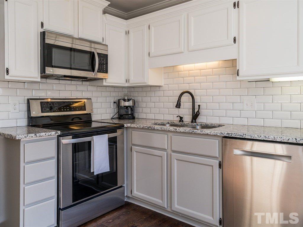5306 Ridgeloch Place Raleigh, NC 27612 - Photo 3 of 23 a kitchen with stainless steel appliances granite countertop grey cabinets a stove a sink and dishwasher
