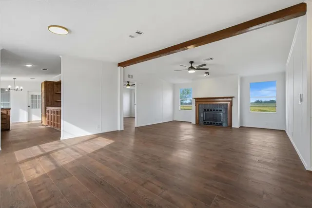 an empty room with wooden floor fireplace and windows