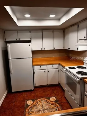 a kitchen with granite countertop a refrigerator and a stove top oven