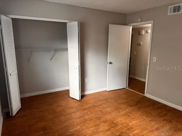 an empty room with closet and wooden floor