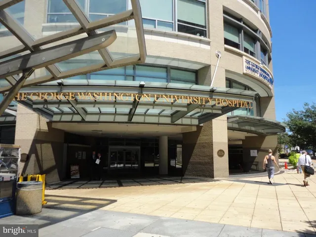 a view of a white house with large windows and a small yard