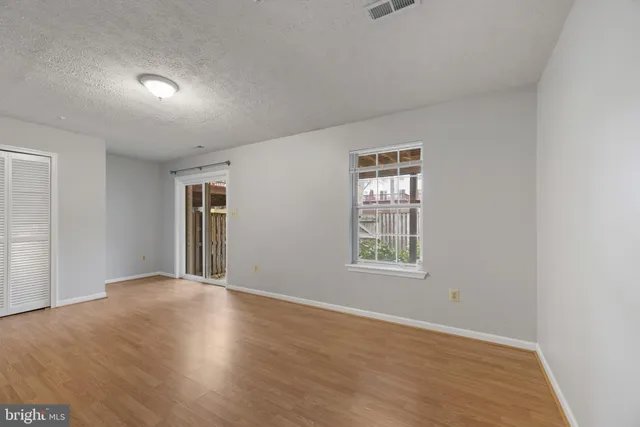 an empty room with wooden floor and windows