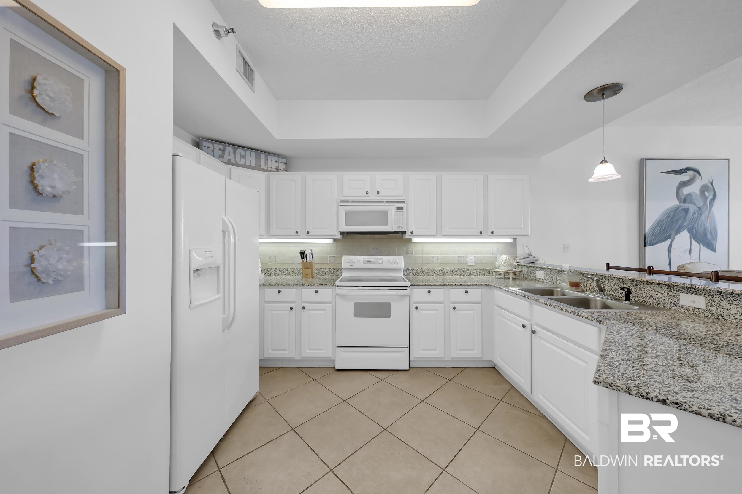 27282 Canal Road, Unit 104 Orange Beach, AL 36561 - Photo 14 of 79 Kitchen with white appliances, a tray ceiling, white cabinets, and hanging light fixtures