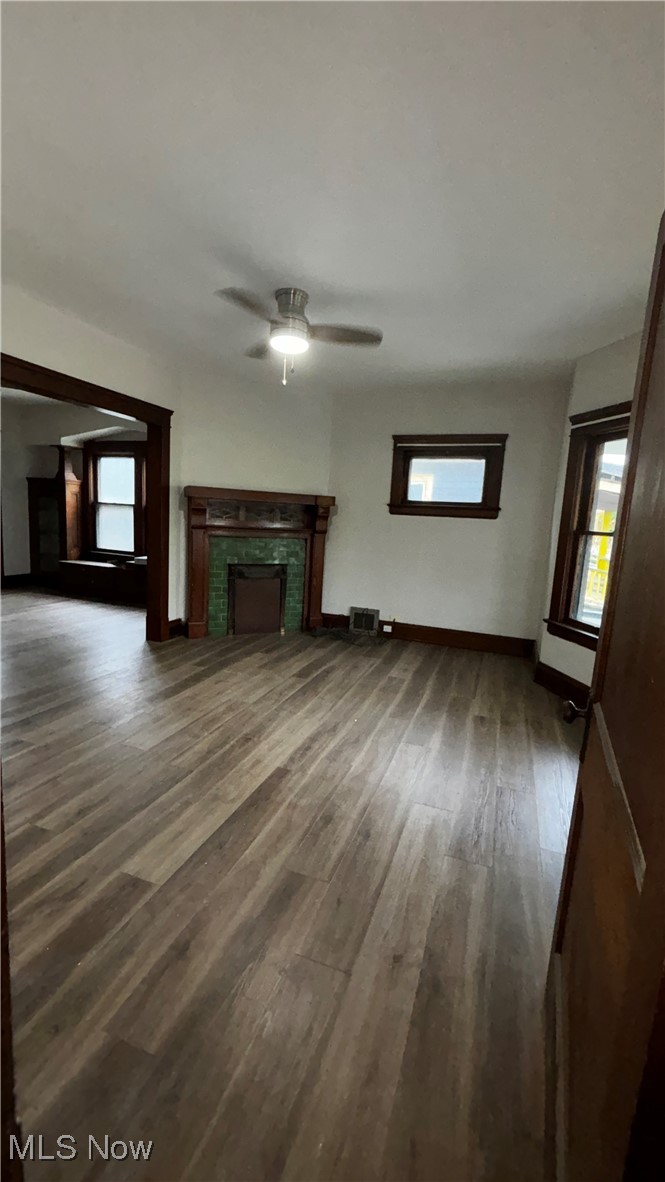 13421 Ashburton Road Cleveland, OH 44110 - Photo 4 of 28 Unfurnished living room featuring dark wood-type flooring, ceiling fan, and a brick fireplace