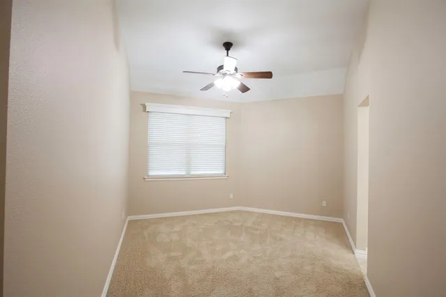 an empty room with chandelier fan and windows