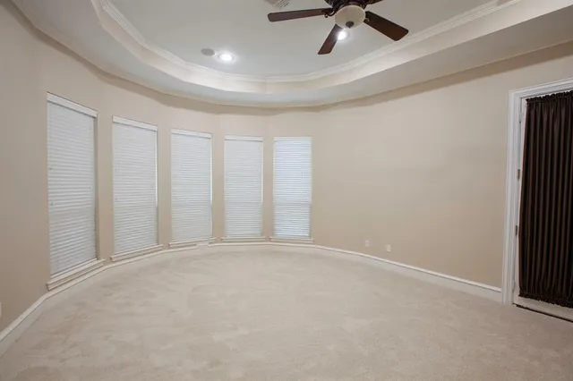 an empty room with chandelier fan and windows