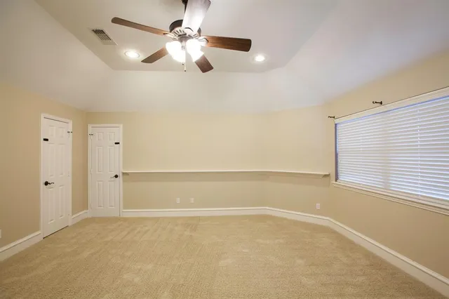 an empty room with chandelier fan and windows