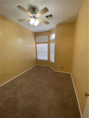 an empty room with windows and fan