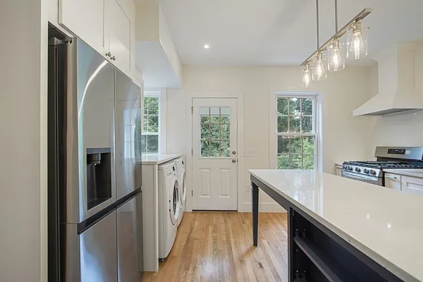 a kitchen with stainless steel appliances granite countertop a refrigerator a sink dishwasher a stove and white countertops with wooden floor