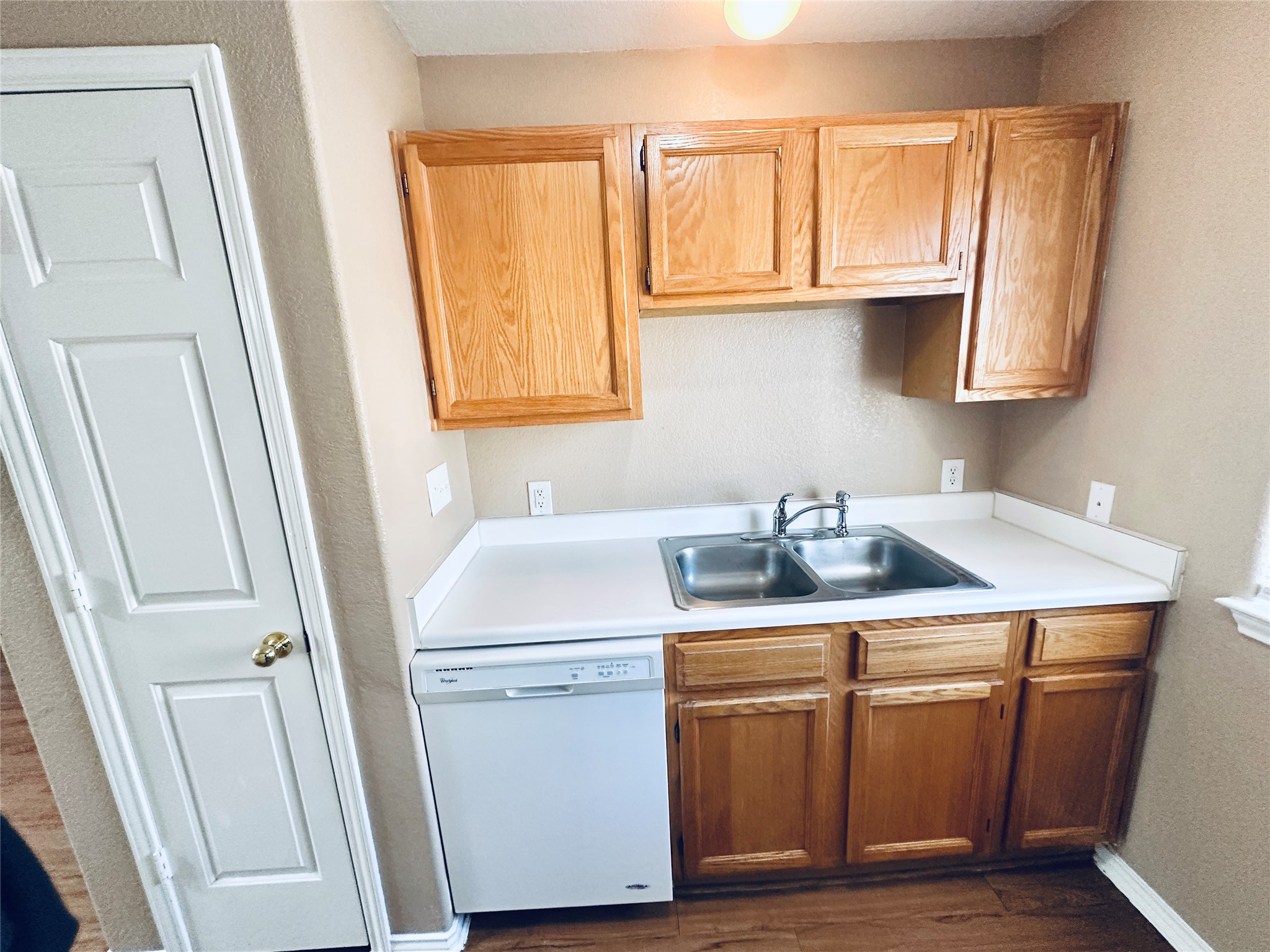 8814 Schick Road, Unit B Austin, TX 78729 - Photo 11 of 36 Kitchen with white dishwasher, light countertops, a textured wall, and dark wood finished floors