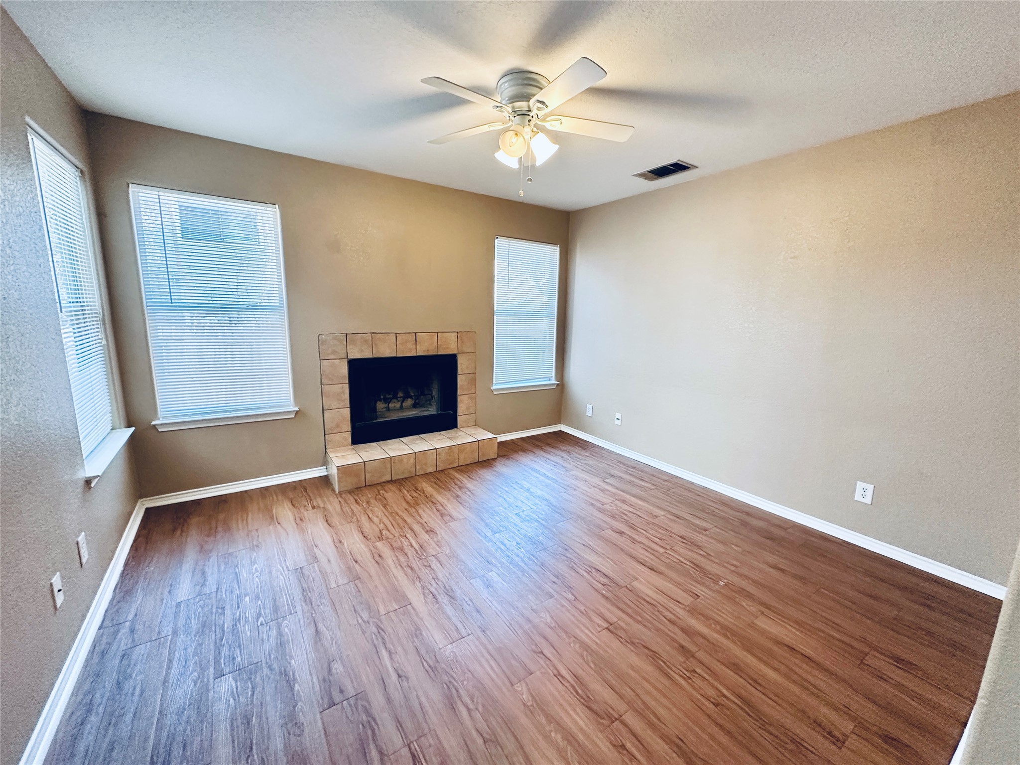 8814 Schick Road, Unit B Austin, TX 78729 - Photo 13 of 36 Unfurnished living room with a ceiling fan, wood finished floors, a fireplace, a textured wall, and a textured ceiling