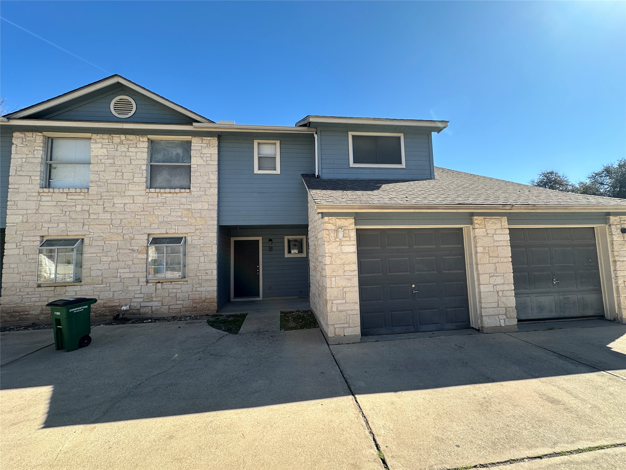 8814 Schick Road, Unit B Austin, TX 78729 - Photo 3 of 36 View of front facade featuring stone siding, driveway, and roof with shingles