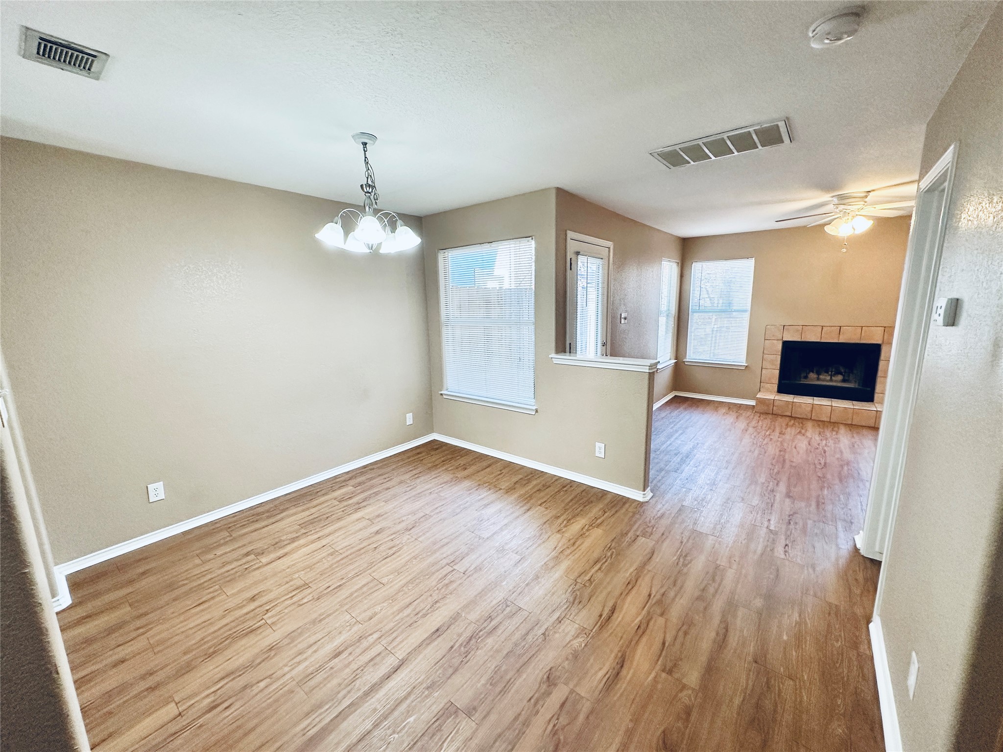 8814 Schick Road, Unit B Austin, TX 78729 - Photo 7 of 36 Unfurnished dining area with light wood-style floors, a fireplace, a textured ceiling, a chandelier, and a ceiling fan