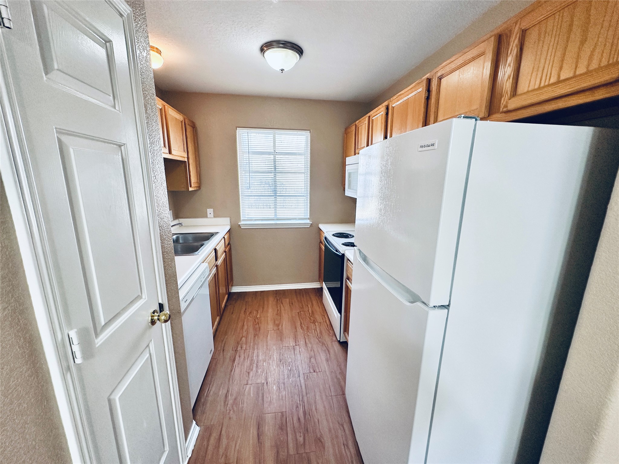 8814 Schick Road, Unit B Austin, TX 78729 - Photo 9 of 36 Kitchen featuring white appliances, dark wood-style floors, light countertops, and wood finish cabinetry