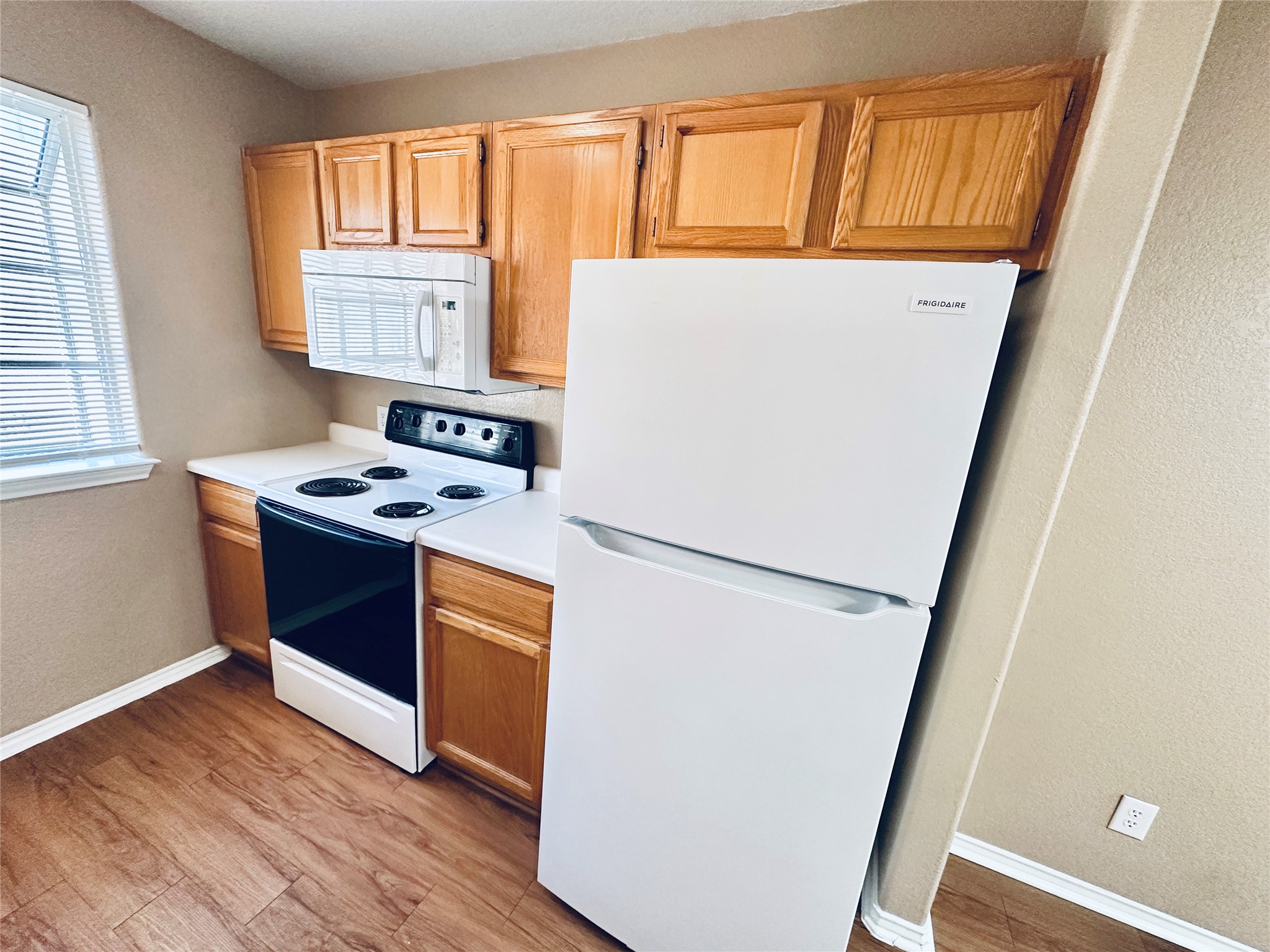 8814 Schick Road, Unit B Austin, TX 78729 - Photo 10 of 36 Kitchen featuring white appliances, light countertops, light wood-style floors, a textured wall, and light wood finish cabinetry