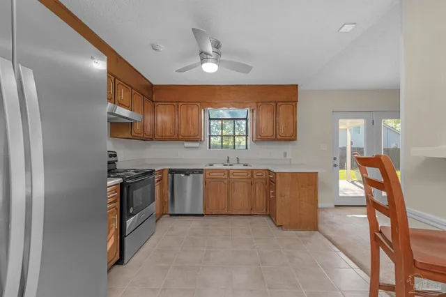 a kitchen with granite countertop a stove top oven a sink dishwasher a dining table and chairs with wooden floor