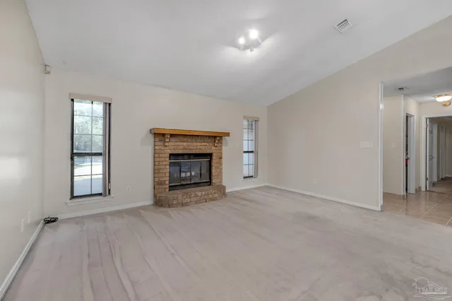 an empty room with windows and fireplace