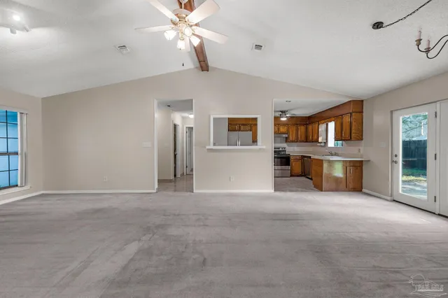 a view of an empty room with a window and a kitchen