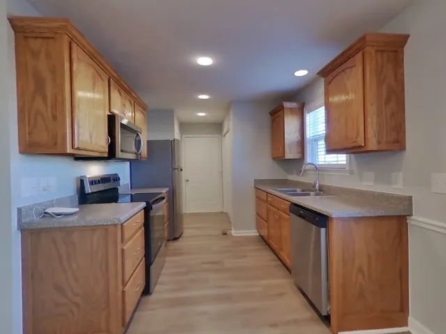 a kitchen with stainless steel appliances granite countertop wooden cabinets a stove top oven a sink and dishwasher
