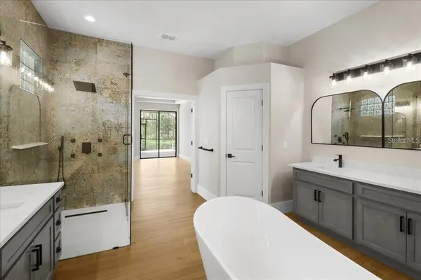 a spacious bathroom with a double vanity sink toilet mirror and bathtub