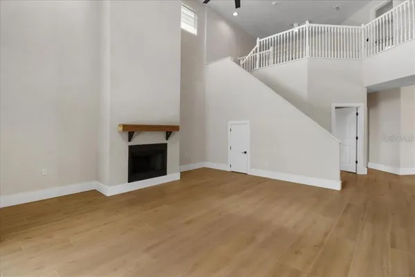 a view of an empty room with wooden floor and a fireplace