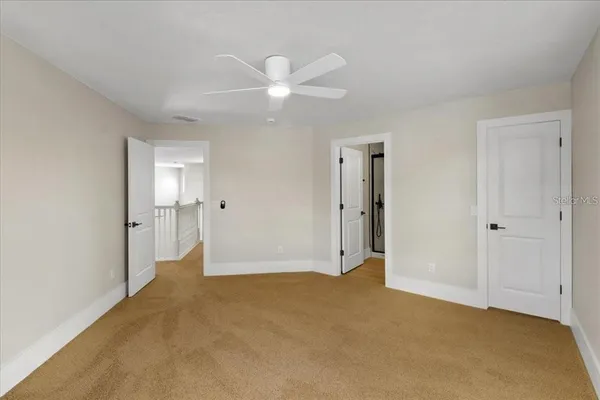 an empty room with an entryway and chandelier fan