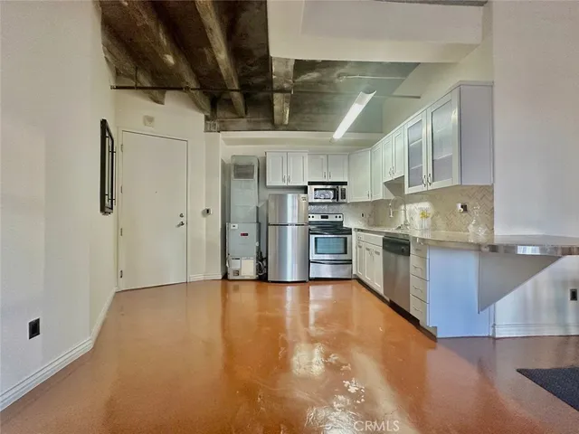 a kitchen with stainless steel appliances a refrigerator a sink a stove and white cabinets