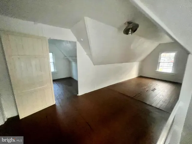 en view of an empty room with wooden floor and a window