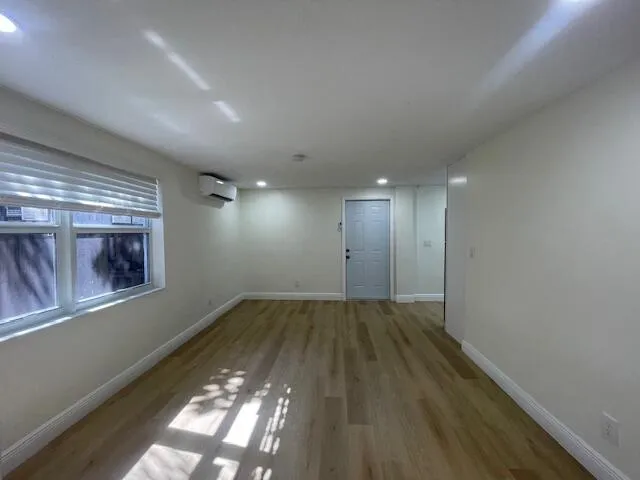 a view of an empty room with wooden floor and a window