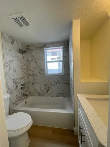 a bathroom with a granite countertop toilet sink and mirror