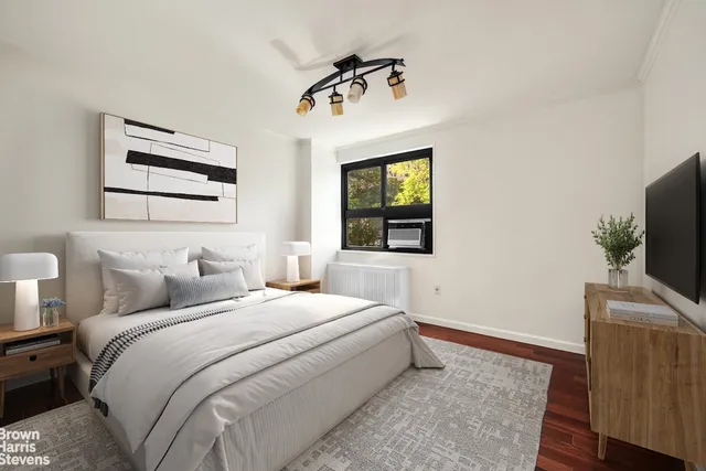 a bedroom with a bed and a flat tv screen on dresser