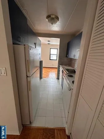a view of a refrigerator in kitchen and an empty room