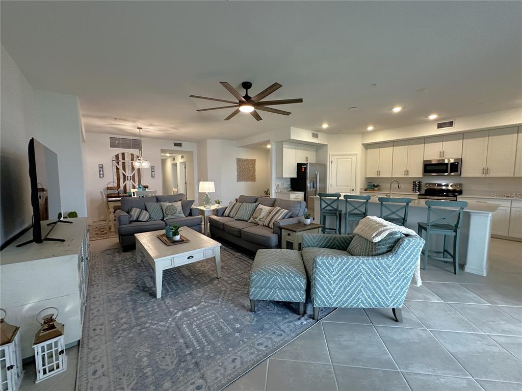 14192 Poppy Fld Loop, Unit 5011 Punta Gorda, FL 33955 - Photo 6 of 48 a living room with couches a flat screen tv and kitchen view