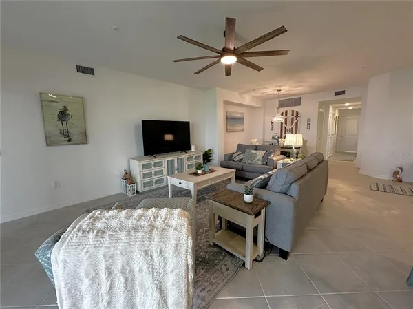 a living room with furniture a flat screen tv and a ceiling fan