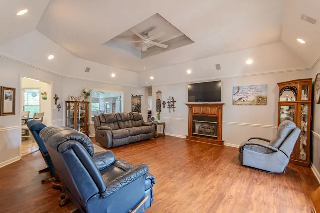 a living room with furniture a fireplace a flat screen tv and kitchen view