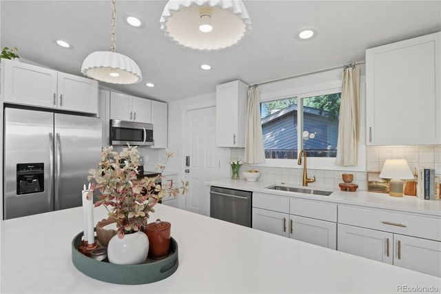 a kitchen with stainless steel appliances kitchen island granite countertop a sink and a refrigerator