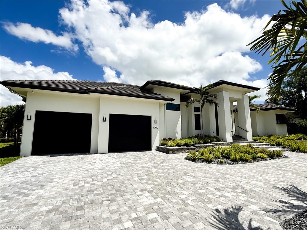 1702 Ludlow Road Marco Island, FL 34145 - Photo 3 of 47 Contemporary residence featuring a paver driveway, two-car garage, and a covered entry with columns