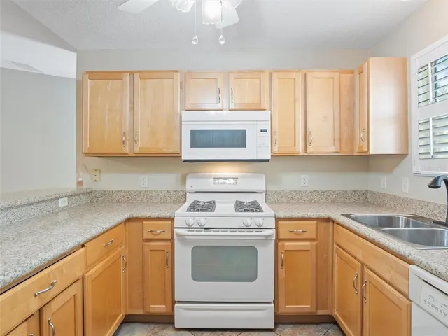 a kitchen with granite countertop white cabinets and white appliances