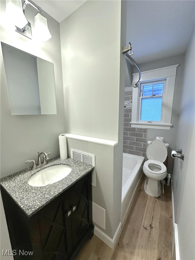 Bathroom featuring wood-type flooring, vanity, and toilet