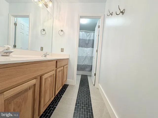 an empty room with wooden floor a ceiling fan and kitchen view