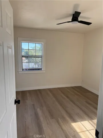 an empty room with wooden floor fan and windows