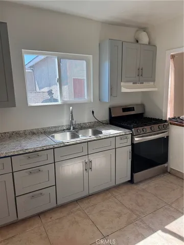 a kitchen with granite countertop a sink a stove and cabinets
