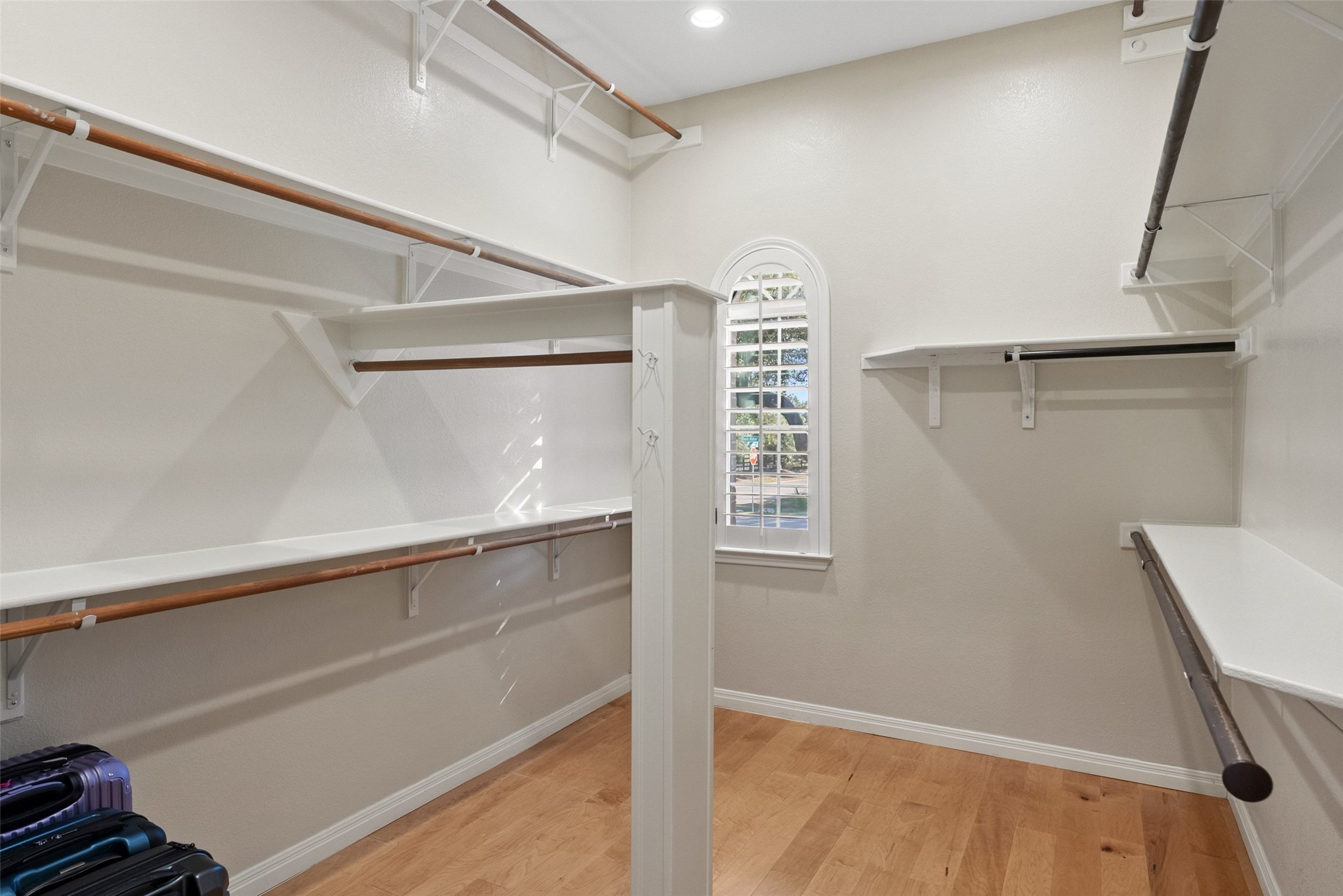 8215 Dark Ridge Cove Austin, TX 78737 - Photo 21 of 40 The large primary closet features ample shelving and hanging rods, plus a window with plantation shutters for natural light.