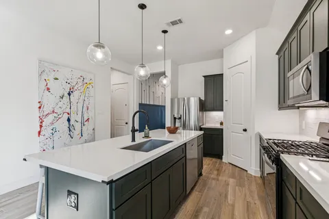 a kitchen with stainless steel appliances granite countertop a sink a stove a refrigerator cabinets and wooden floor