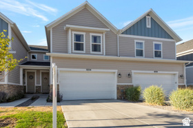 Two-story exterior with neutral siding, stone accents, two single-car garages, and a concrete driveway