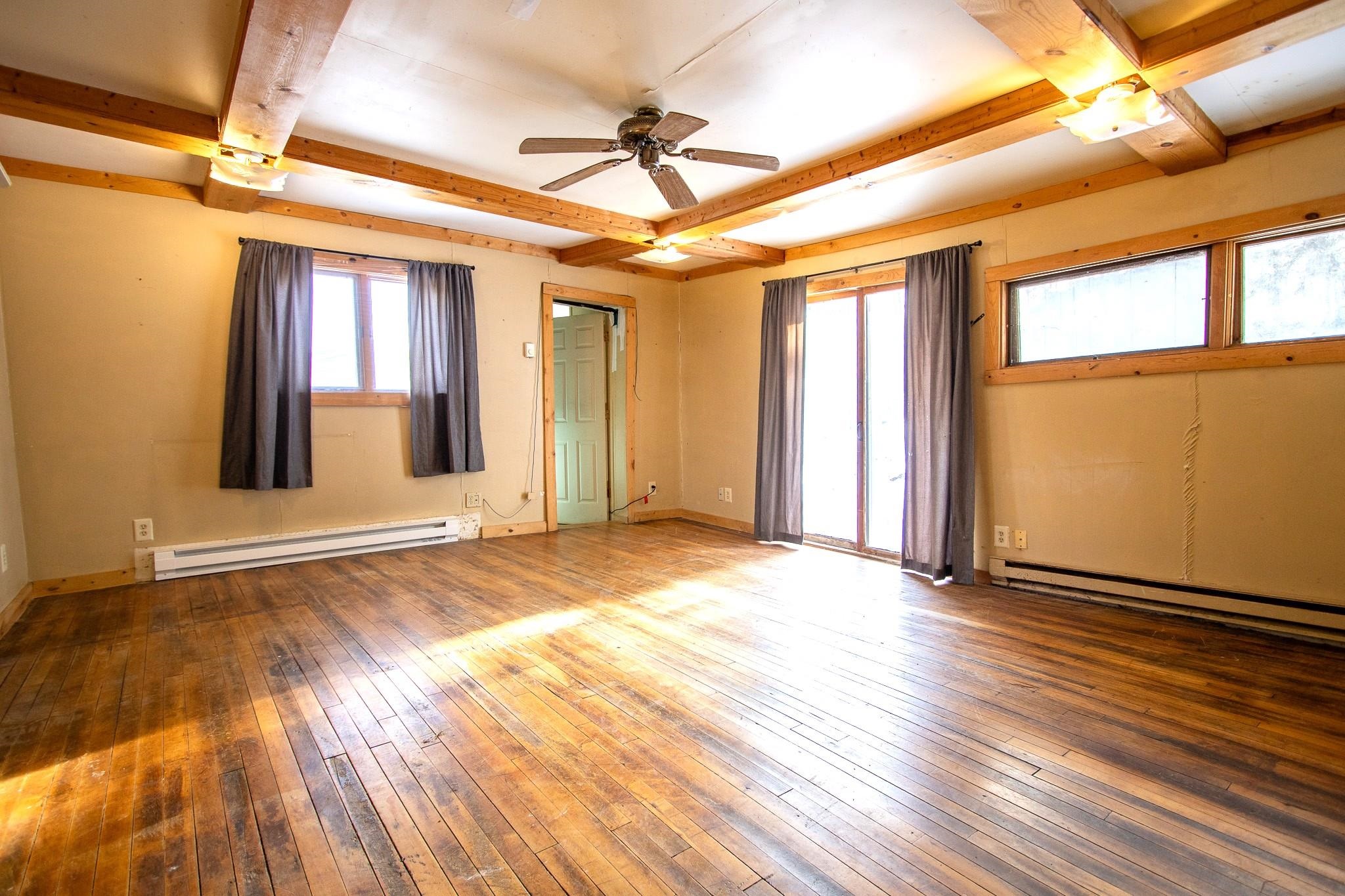 3946 East Calvary Road Duluth, MN 55803 - Photo 3 of 12 Spare room featuring beamed ceiling, baseboard heating, wood-type flooring, and ceiling fan