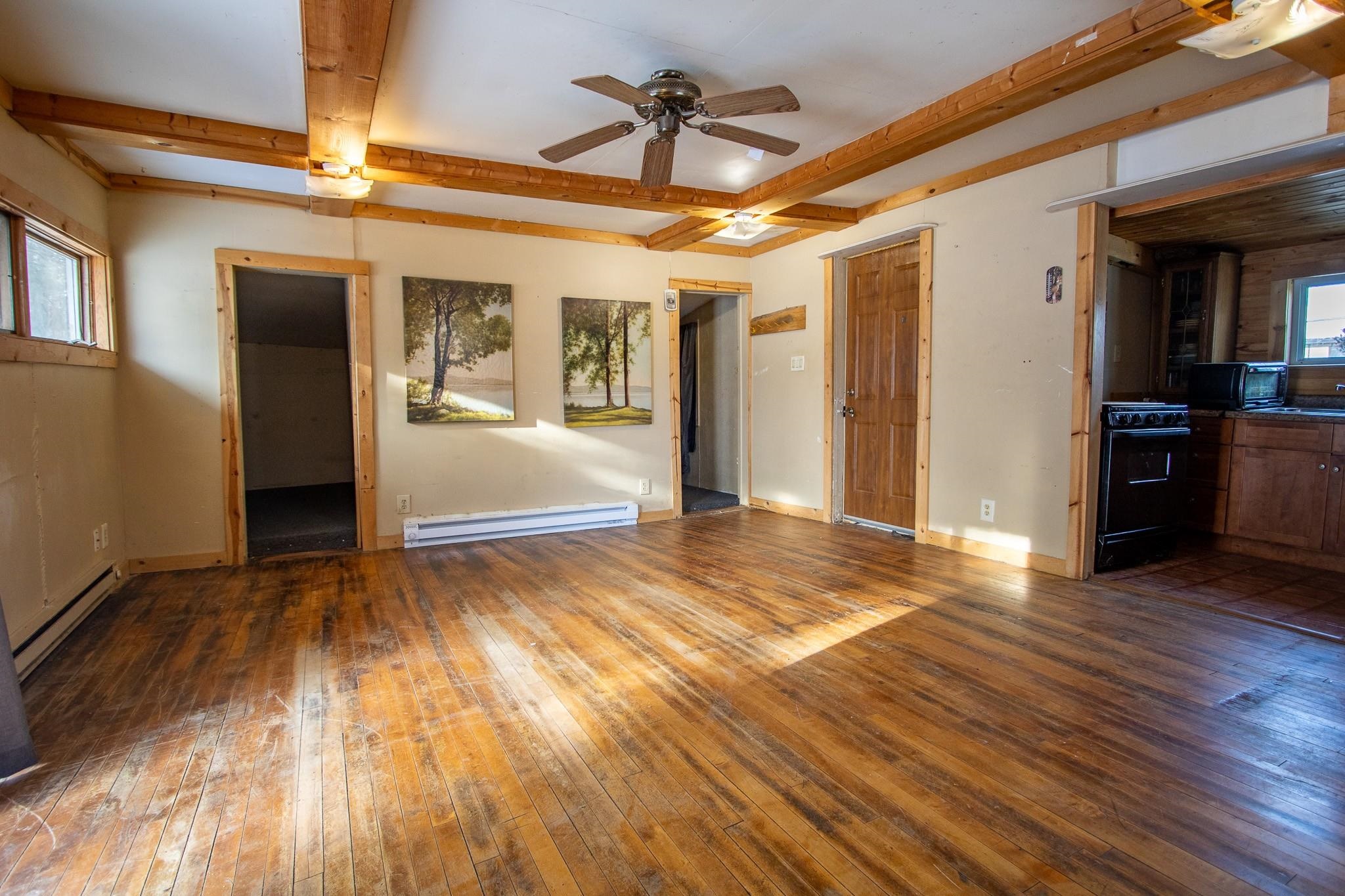 3946 East Calvary Road Duluth, MN 55803 - Photo 4 of 12 Unfurnished living room featuring beam ceiling, dark wood finished floors, a baseboard radiator, ceiling fan, and baseboard heating