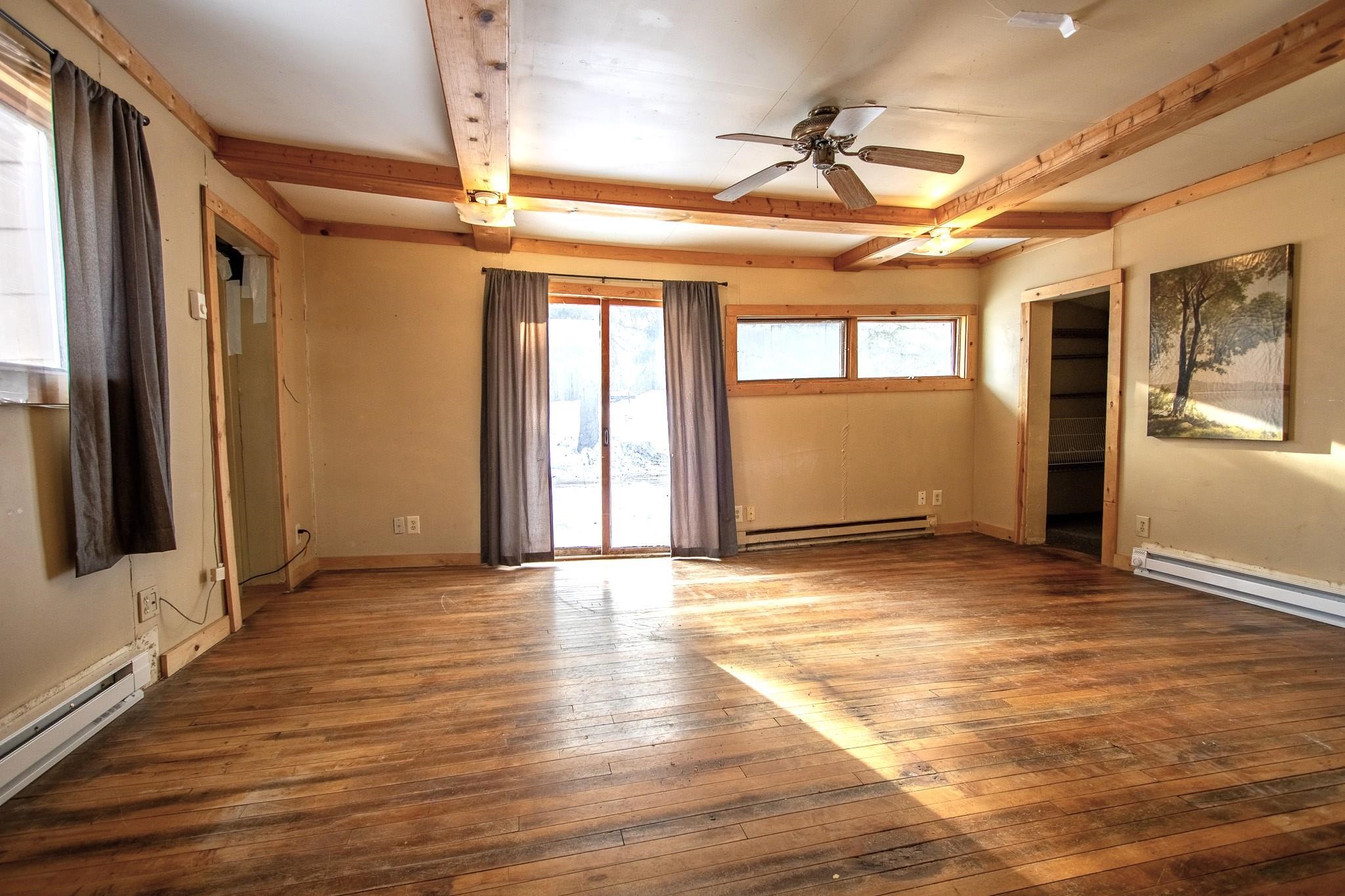 3946 East Calvary Road Duluth, MN 55803 - Photo 6 of 12 Empty room with beam ceiling, wood-type flooring, a ceiling fan, and a baseboard radiator