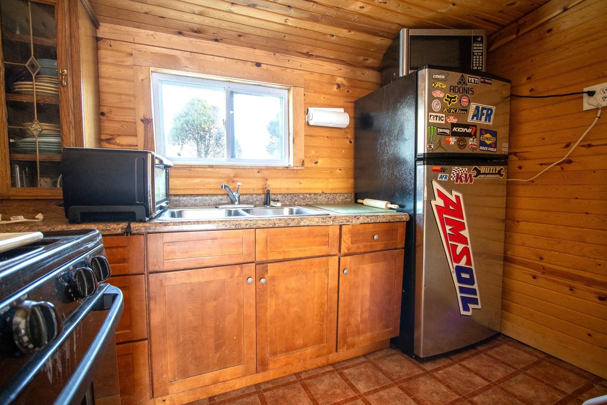 3946 East Calvary Road Duluth, MN 55803 - Photo 7 of 12 Kitchen with wooden walls, appliances with stainless steel finishes, brown cabinetry, wood ceiling, and vaulted ceiling